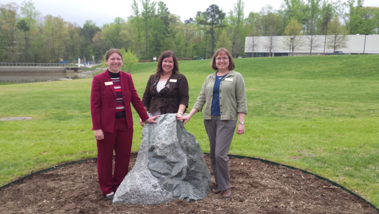 Figure 11: Geologists Dr. Sara Rutzky, Stephanie Rollins, and Gretchen Miller pose with one of the boulders at Northern Wake Campus after the April 14, 2015 dedication ceremony.