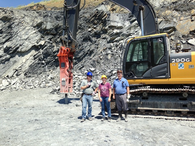 Figure 4: Geologists Tyler Clark, Dr. Sara Rutzky, and Dr. Ken Howard pose in front of a hydraulic hammer during a visit to a quarry to select boulders for the Outdoor Geology Lab in May 2014.