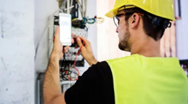 Image of technician wearing hard hat testing fiber-optic line