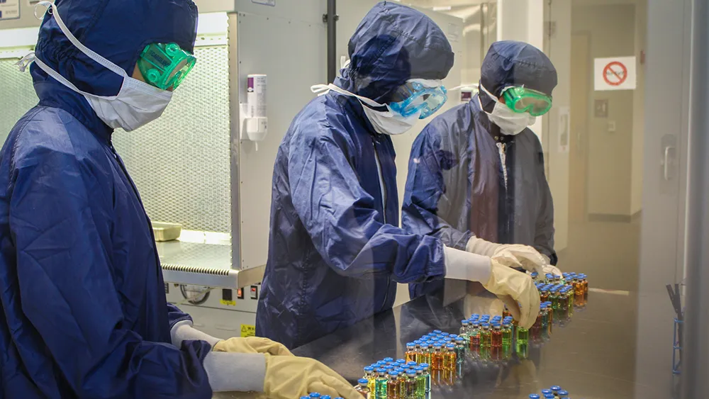 Students dressed in blue gowns and masks in a biotechnology training class