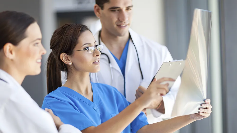 Three health care workers check a patient's chart.