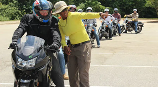 image of a Wake Tech instructor teaching a motorcycle rider in front of a line of other riders