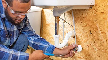 Image of a plumber installing a sink water line