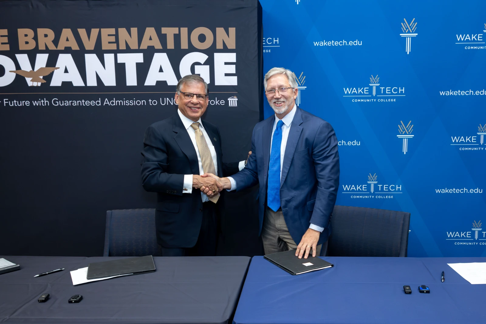 UNC-Pembroke Chancellor Dr. Robin Gary Cummings, left, and Wake Tech President Dr. Scott Ralls shake hands after signing the transfer agreement.