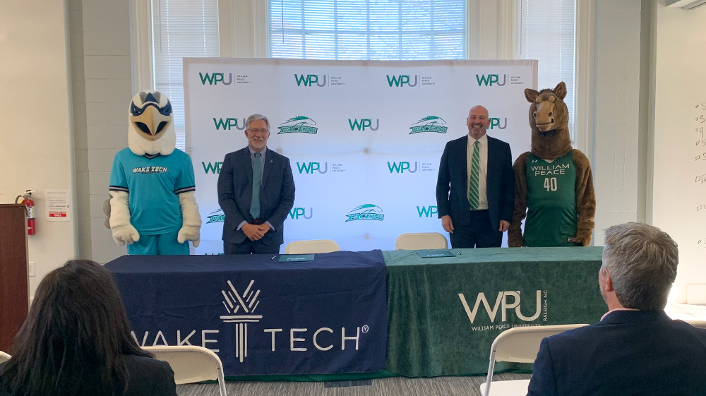 Wake Tech President Dr. Scott Ralls and Talon, the college's mascot, pose with William Peace University President Brian Ralph and that school's mascot, Pacer, during a signing ceremony.
