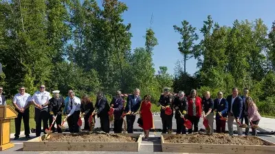 A flag flies from fire engine ladders during the groundbreaking ceremony for the Advanced Fire and Rescue Training Complex at Wake Tech East.