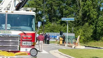 A flag flies from fire engine ladders during the groundbreaking ceremony for the Advanced Fire and Rescue Training Complex at Wake Tech East.