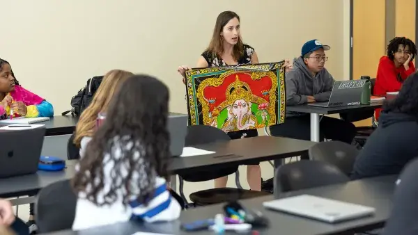 Dana Trent shows off a Hindu tapestry to her World Religions class.