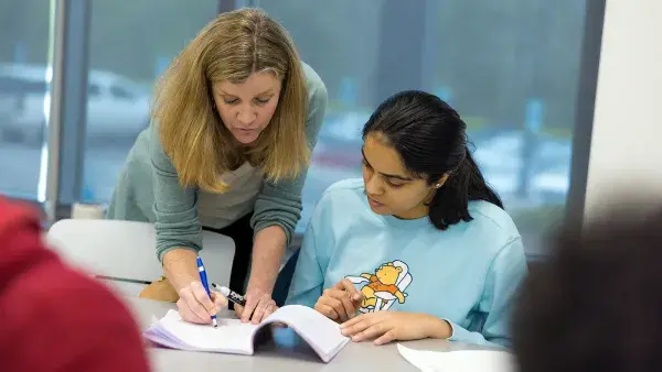 Kelly Markson works with a student in an economics class.